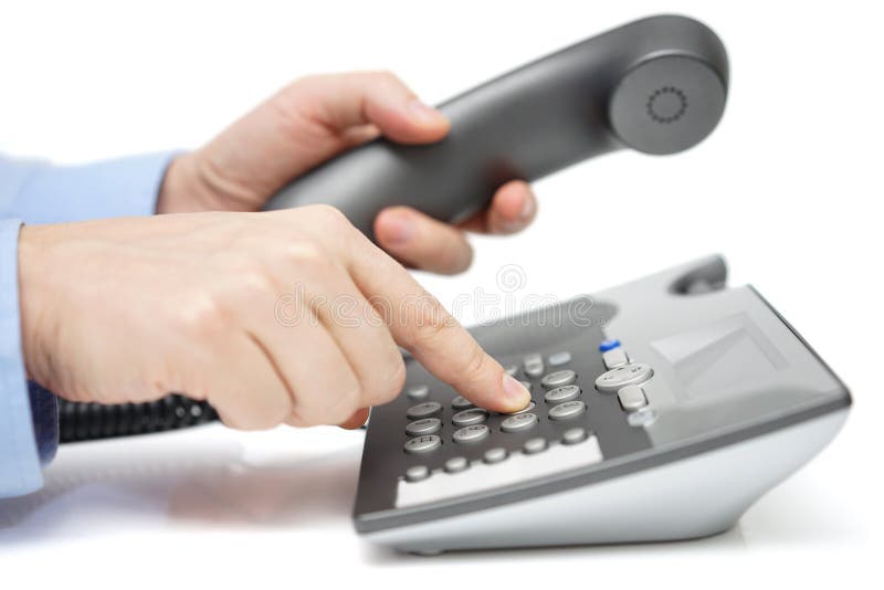 Businessman is dialing telephone number with handset in hand