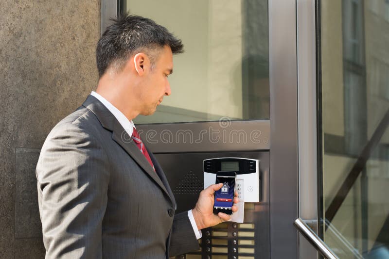 Businessman Disarming Security System Of Door With Smartphone royalty free stock photo