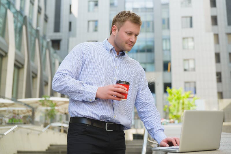 Businessman drinking coffee and working on laptop outdoor royalty free stock image Businessman drinking coffee and working on laptop outdoor royalty free stock image