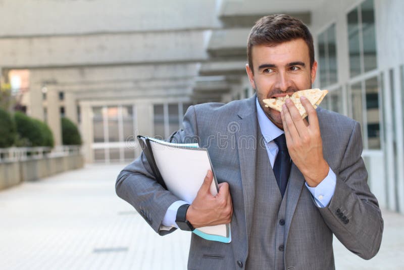 Businessman eating a sandwich on the go stock images