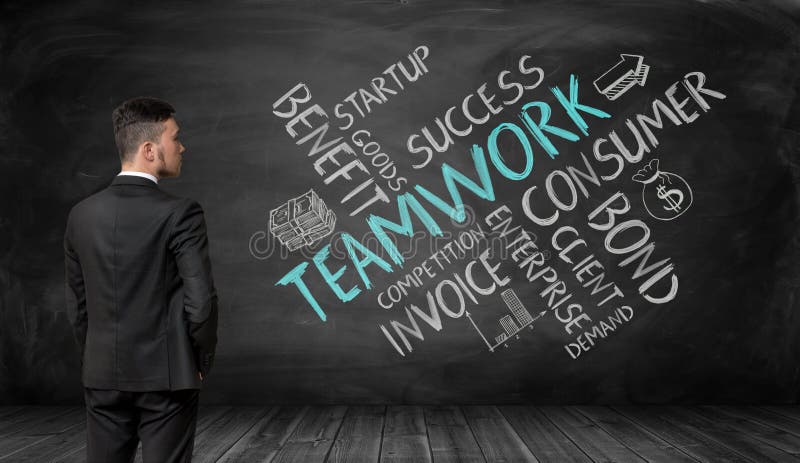 Businessman in full growth looking at black wall with sketches of teamwork formation. royalty free stock images Businessman in full growth looking at black wall with sketches of teamwork formation. royalty free stock images