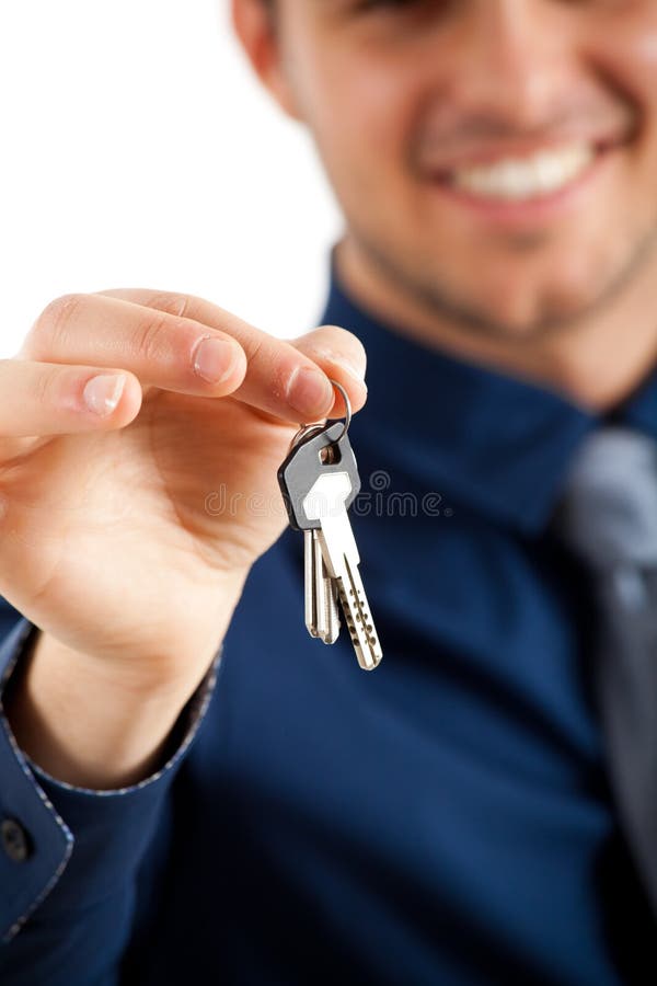 Handsome businessman is giving keys to some clients. Focus on the keys. Handsome businessman is giving keys to some clients. Focus on the keys