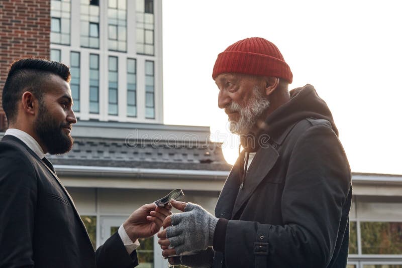 Senior homeless men getting money from businessman, smiling happy beggar. People, relationship concept. Senior homeless men getting money from businessman, smiling happy beggar. People, relationship concept