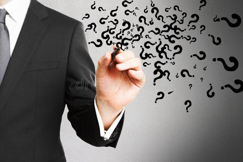Businessman hand drawing abstract question marks on concrete wall background. stock photography