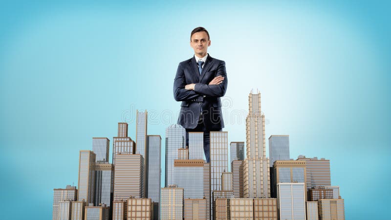 A businessman with his hands crossed standing behind a small model of a business district.