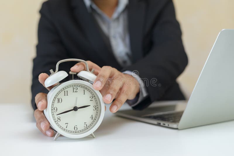 Businessman Holding Analog White Alarm Clock for Setting Time at Office