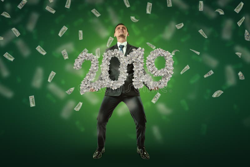 Businessman holding a `2019` money sign with US dollars in the air on green background. Banking and finance. Business success. Management and production.