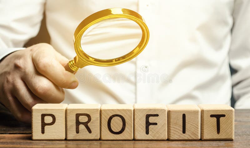 Businessman holds a magnifying glass over the word Profit. The concept of profitability and performance of business. Analysis of