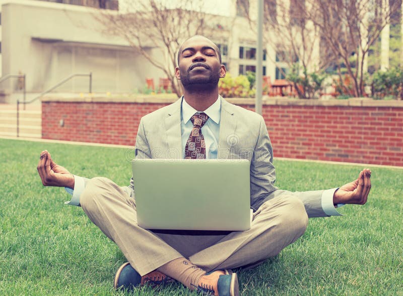 Businessman with laptop meditating in lotus pose taking a deep breath stock photo Businessman with laptop meditating in lotus pose taking a deep breath stock photo