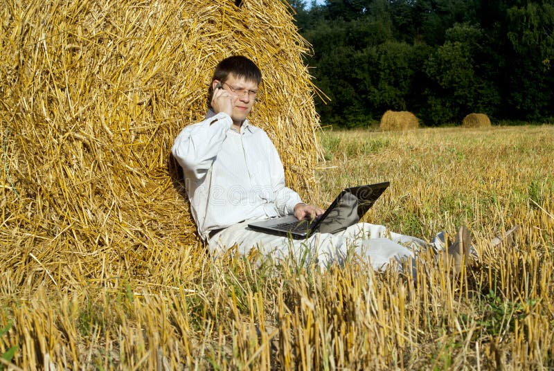 Businessman with laptop near the haystacks