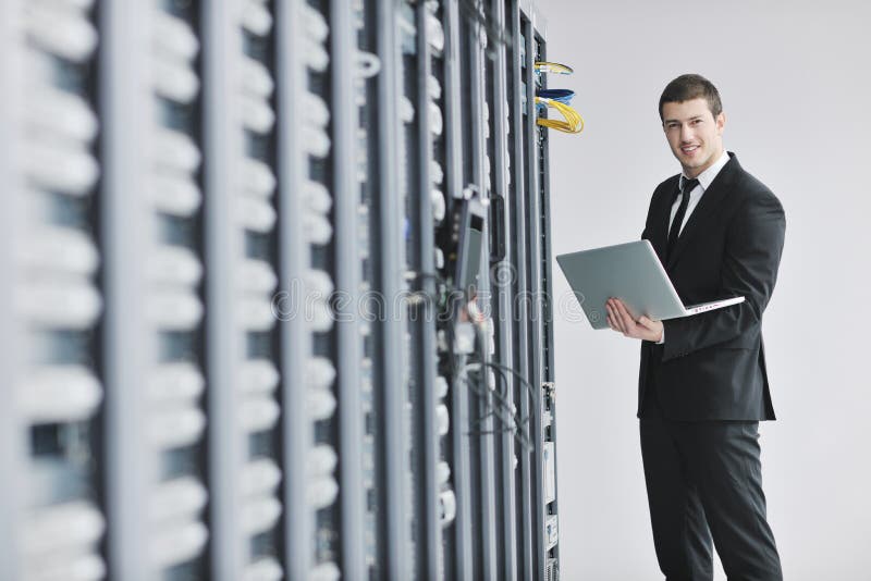 Businessman with laptop in network server room