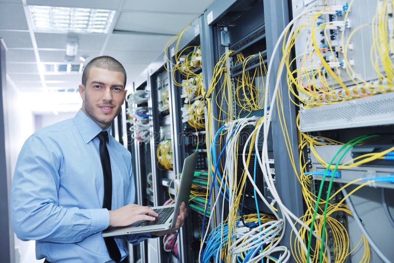 Businessman with laptop in network server room