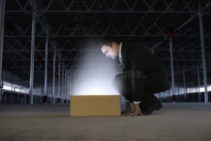 Businessman Looking At Glowing Box In Empty Warehouse royalty free stock photos