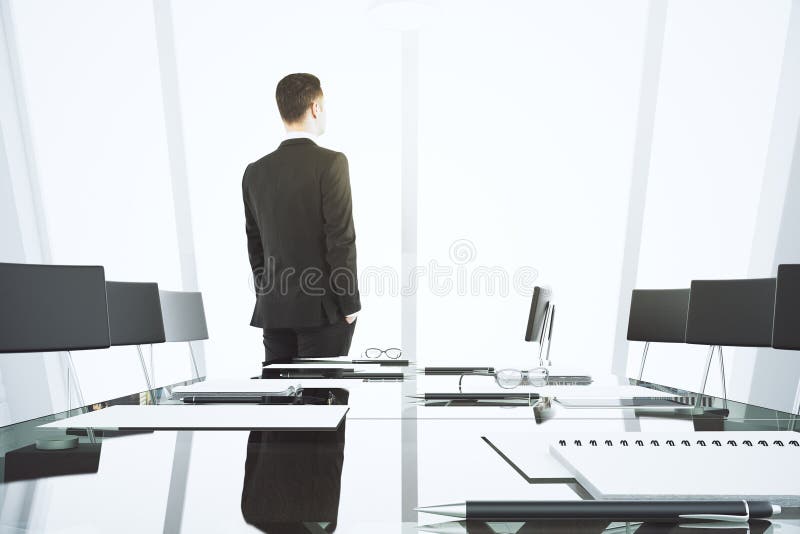Businessman looking out the window in modern conference room wit