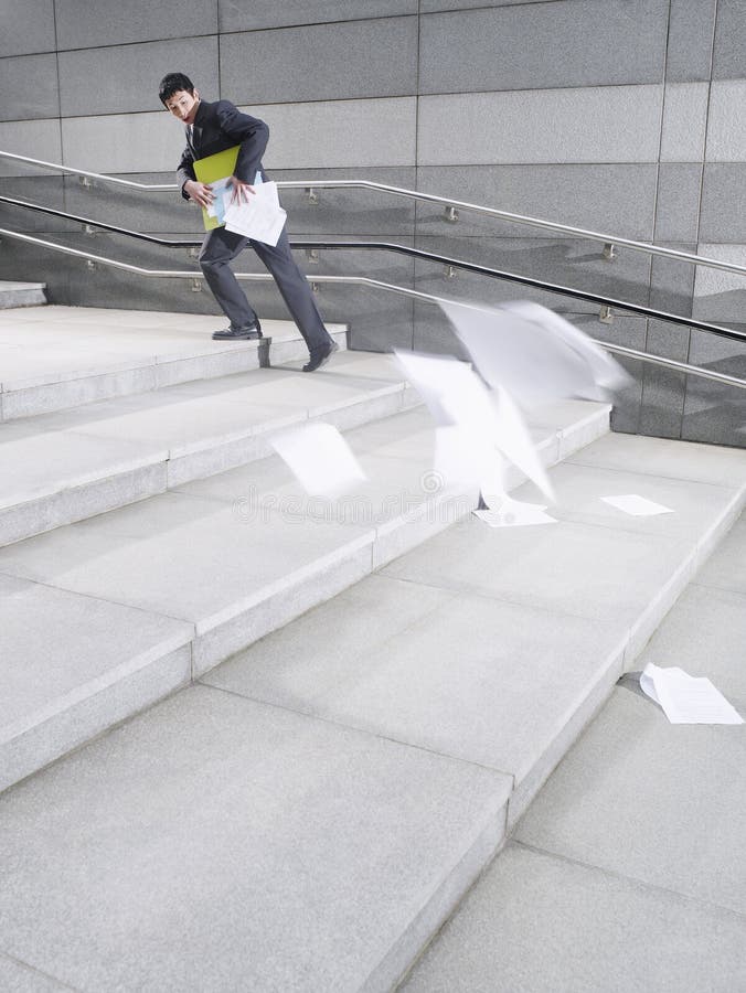 Businessman Losing Papers From Briefcase While Walking Up Steps