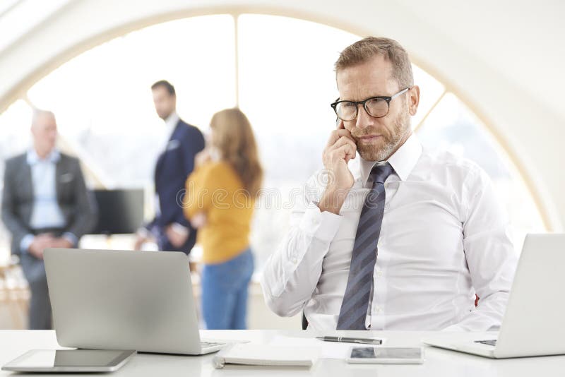 Businessman making call and using laptop at the office