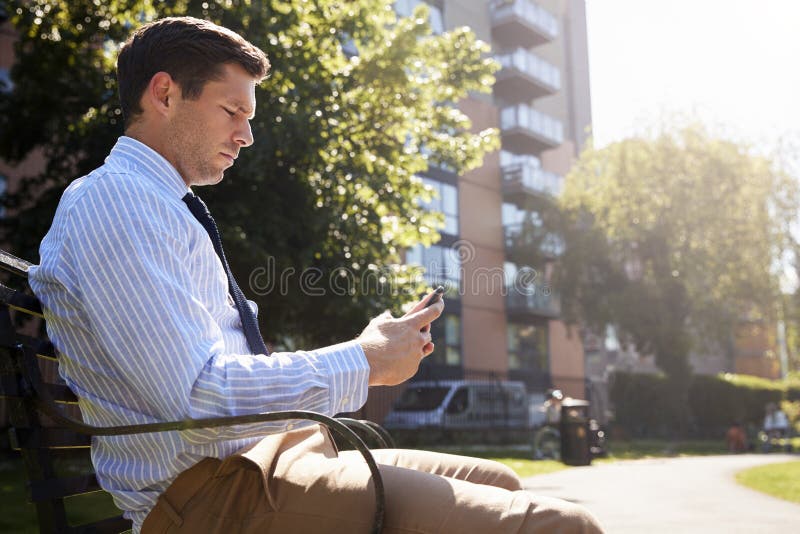 Businessman Outdoors Using Mobile Phone On Lunch Break In Park royalty free stock images Businessman Outdoors Using Mobile Phone On Lunch Break In Park royalty free stock images