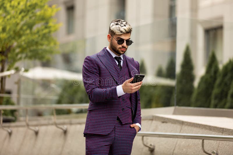 Businessman Outside Office On Mobile Phone. Man wearing at violet luxery three-piece suit