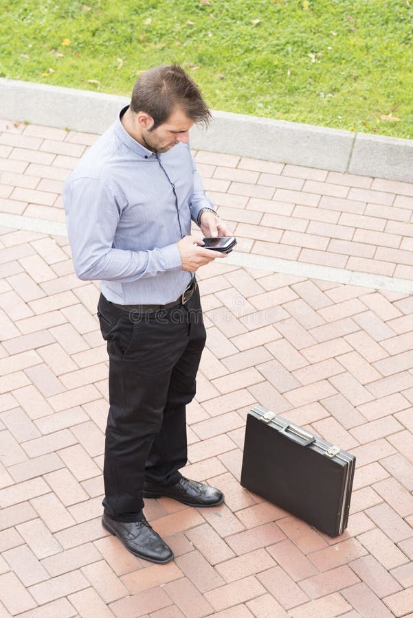 Businessman with phone and briefcase in the street.