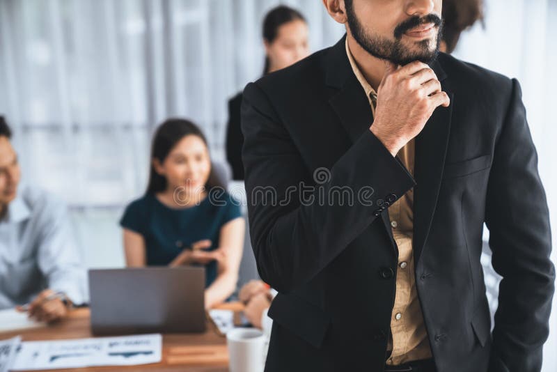 Businessman poses confidently portrait in busy meeting room. Concord stock image