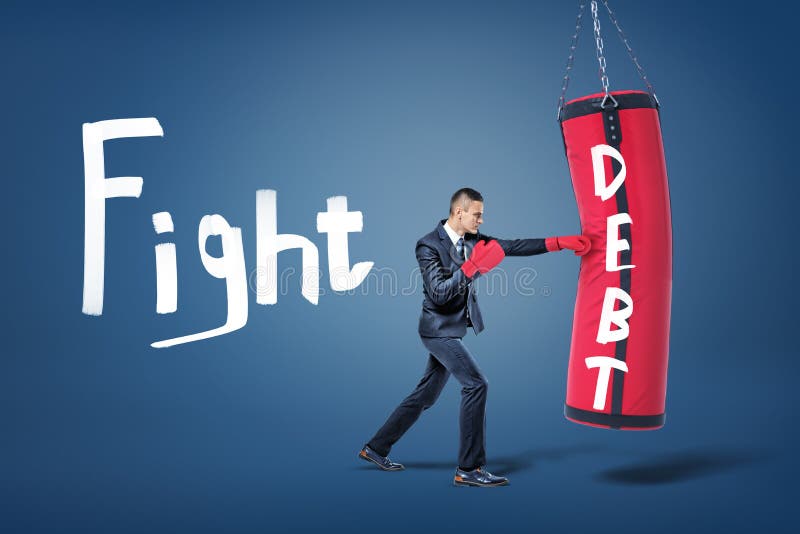 A businessman in red gloves hits a large red boxing bag with a word Debt written on it. stock image A businessman in red gloves hits a large red boxing bag with a word Debt written on it. stock image