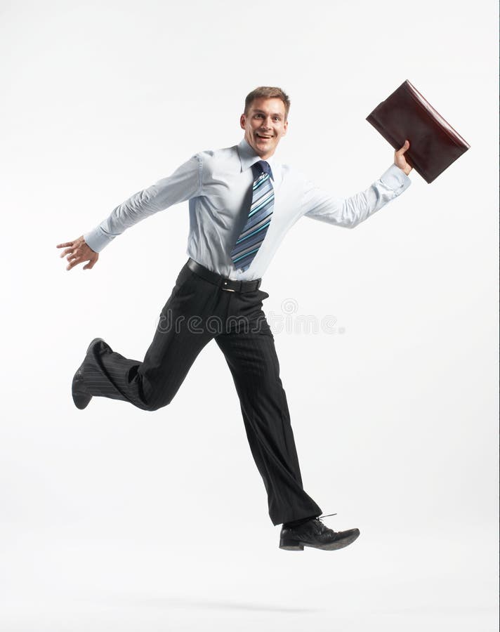 A studio view of a smiling businessman running and carrying an executive folder.