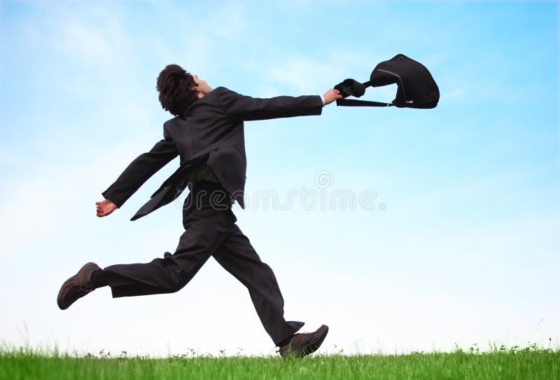 Businessman running on meadow with bag stock photo