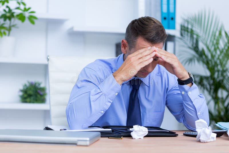 Businessman with Severe Headache Sitting at Office Desk Stock Photo