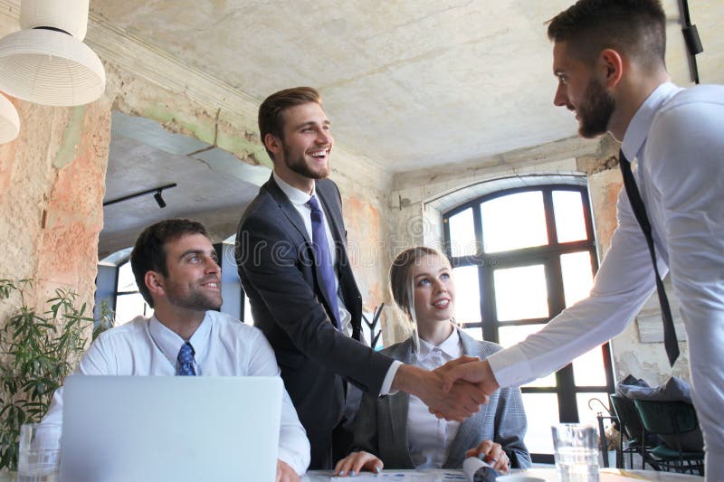 Businessman shaking hands to seal a deal with his partner and colleagues in office