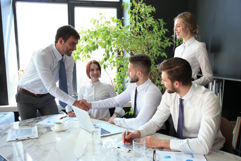 Businessman shaking hands to seal a deal with his partner and colleagues in office royalty free stock image Businessman shaking hands to seal a deal with his partner and colleagues in office royalty free stock image