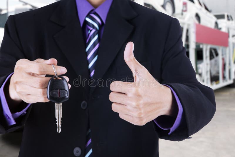 Businessman shows OK sign and a car key