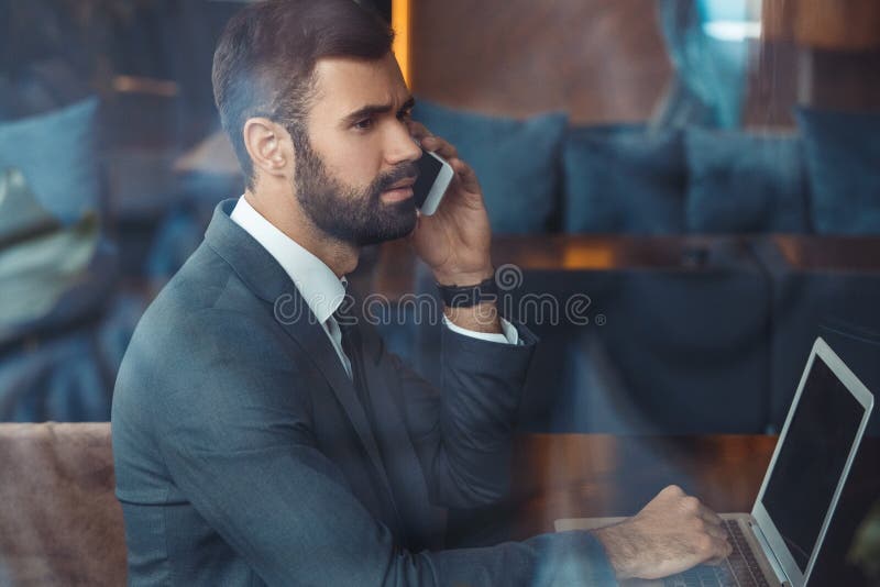 Businessman sitting in a business center restaurant with laptop phone call royalty free stock images Businessman sitting in a business center restaurant with laptop phone call royalty free stock images