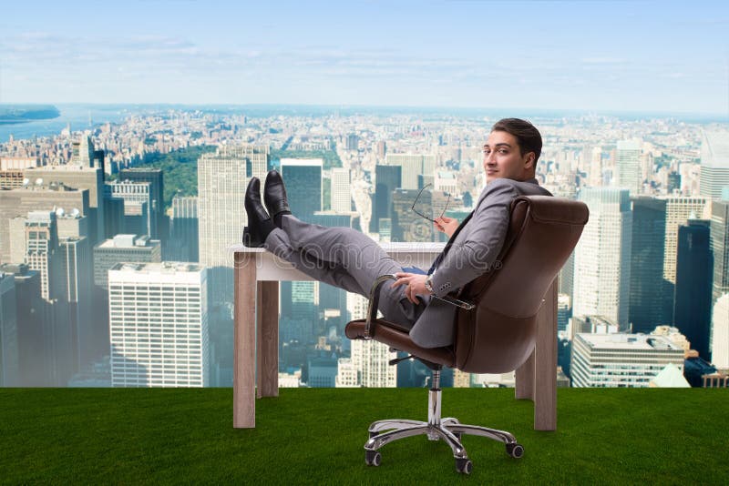 The businessman sitting on grass with city view stock photo The businessman sitting on grass with city view stock photo
