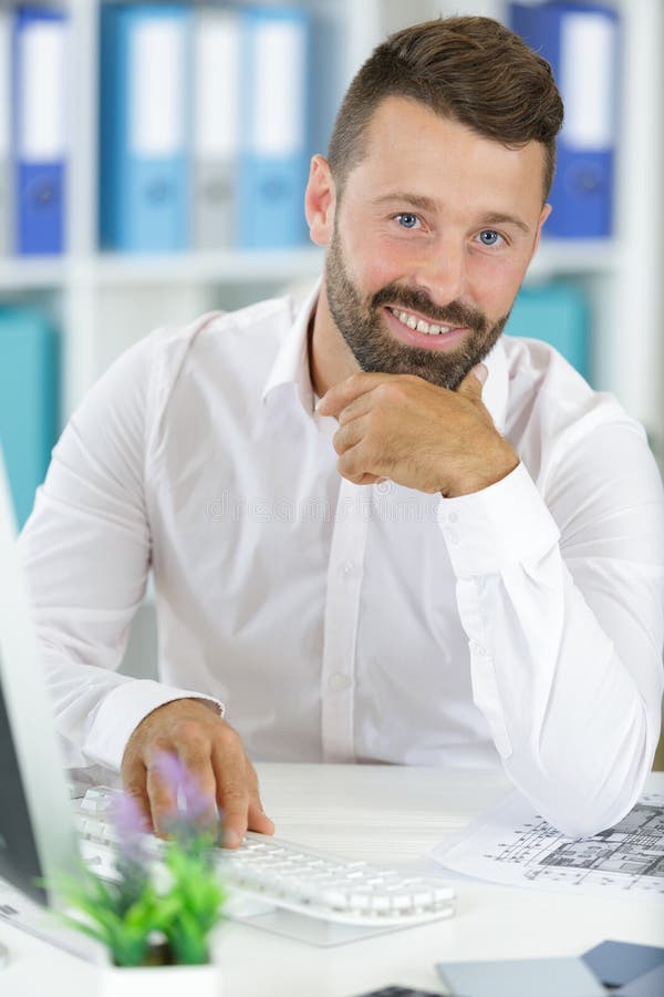 Businessman sitting at office desk working on laptop computer stock images