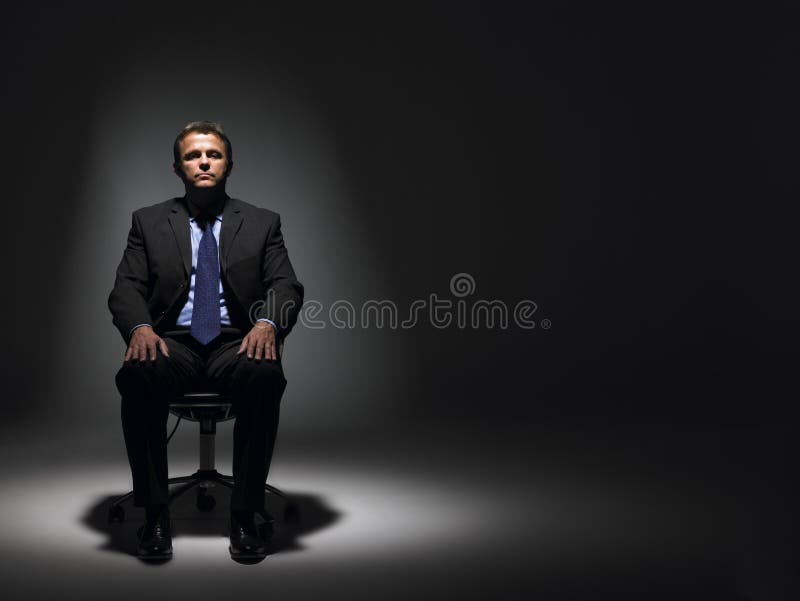 Businessman Sitting In Spotlight looking ahead