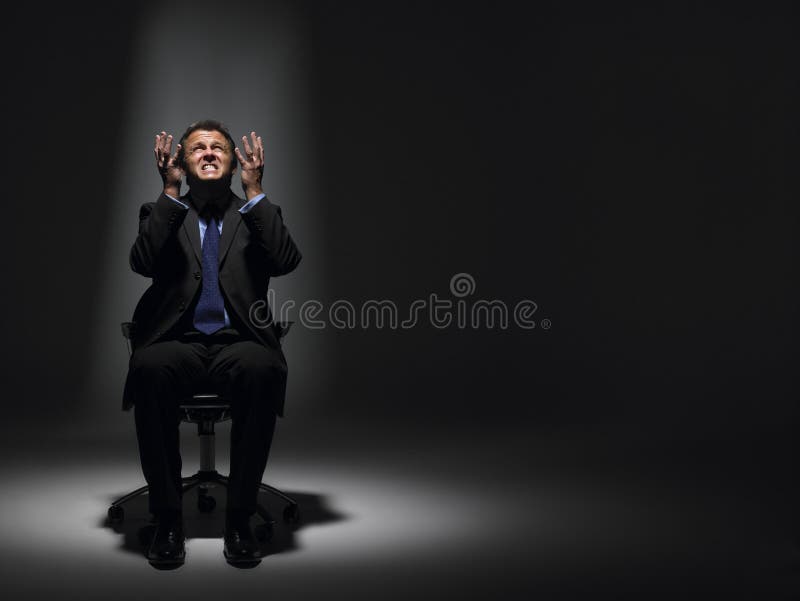 Businessman Sitting In Spotlight looking up