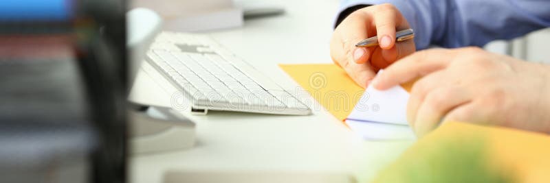 Businessman is sitting at table in office holding yellow envelope and taking out sheet of notification of a received