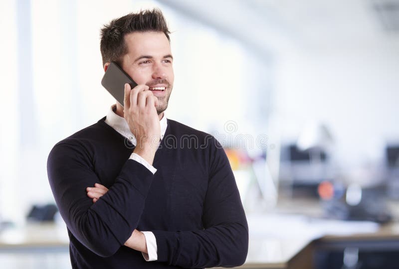 Businessman standing in the office and talking with somebody on his mobile phone stock photo Businessman standing in the office and talking with somebody on his mobile phone stock photo