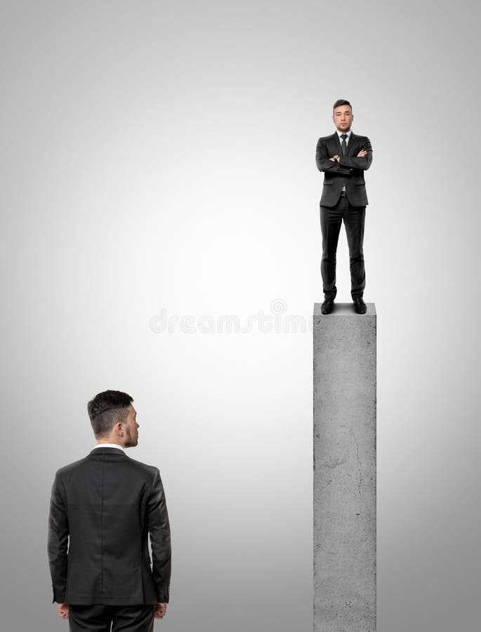 Businessman standing on peak of a concrete pillar looking at the other businessman stock photography Businessman standing on peak of a concrete pillar looking at the other businessman stock photography