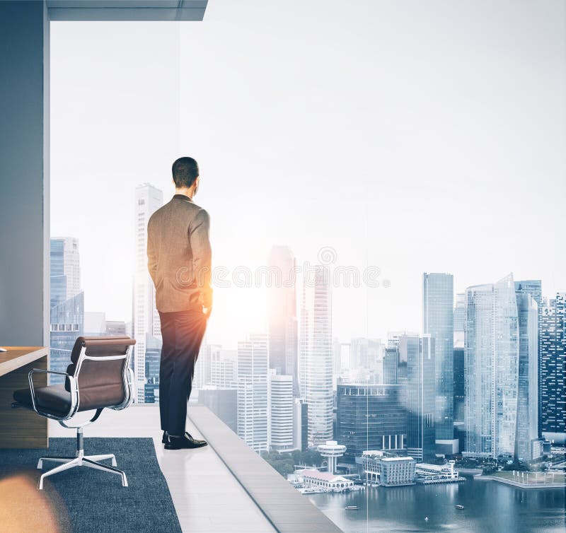 Businessman stands in contemporary office and looking at the city. Square royalty free stock photography Businessman stands in contemporary office and looking at the city. Square royalty free stock photography