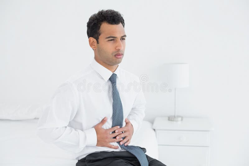 Businessman with stomach pain sitting on bed royalty free stock photos Businessman with stomach pain sitting on bed royalty free stock photos