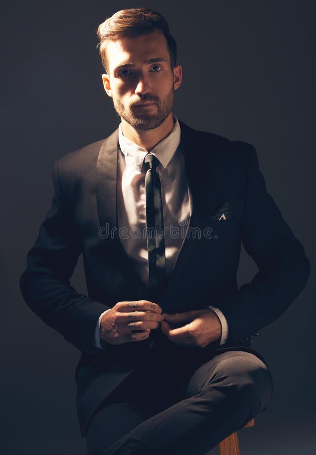 Young businessman with tattooed face fastening tie stock photo