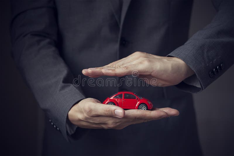Businessman in suit with two hands in position to protect a car (focus on hand, blur out the suit). It indicates many aspects such as car insurance coverage, support, assurance, reliability.