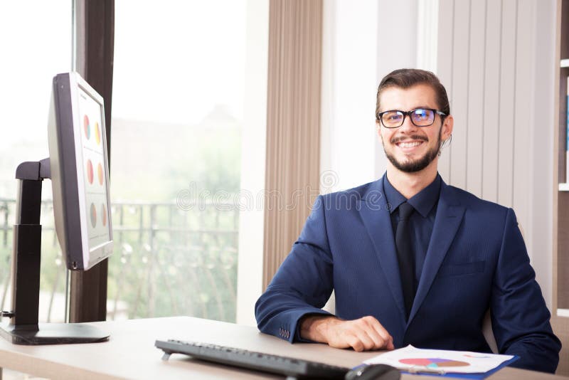 Businessman in suit working at his computer next to a glass wind royalty free stock photo Businessman in suit working at his computer next to a glass wind royalty free stock photo
