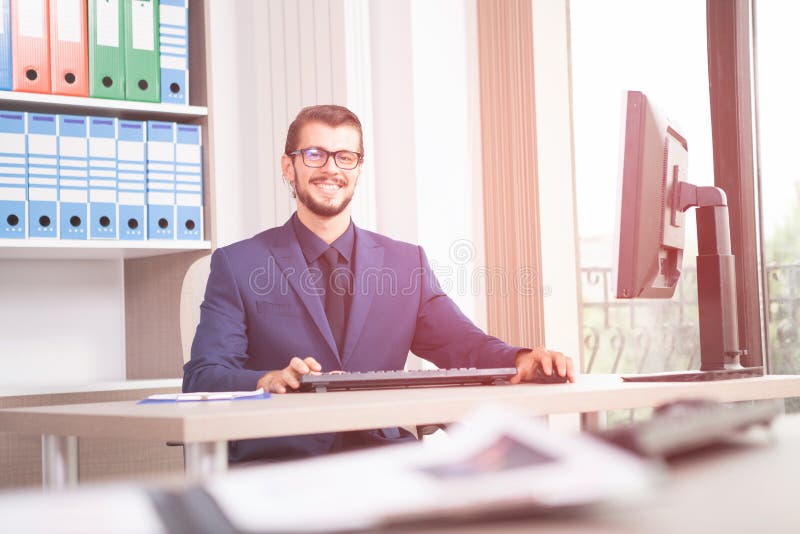 Businessman in suit working at his computer next to a glass wind royalty free stock image Businessman in suit working at his computer next to a glass wind royalty free stock image