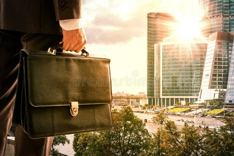 Businessman with suitcase against modern city stock photography