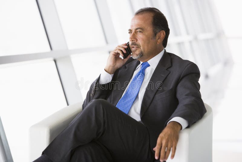 Businessman talking on mobile phone in lobby stock images