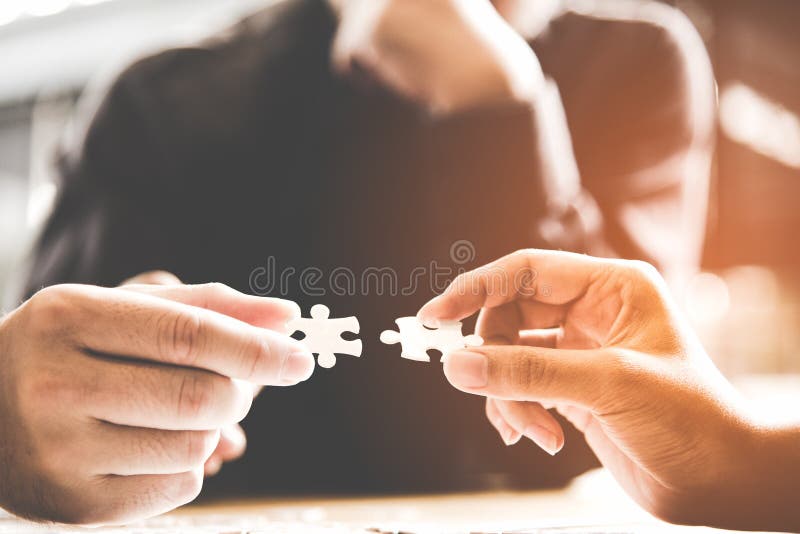 Uomo d'affari di lavoro in team, tenendo due puzzle di collegamento paio di pezzo di puzzle di corrispondenza per finalità di destinazione, il successo e la start up nuovo progetto in ufficio.