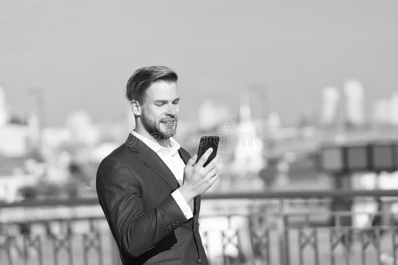 Businessman use smartphone with smile. Happy man with mobile phone on sunny terrace. Great business news. Communication stock image Businessman use smartphone with smile. Happy man with mobile phone on sunny terrace. Great business news. Communication stock image