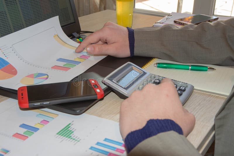 Businessman using a calculator to calculate the numbers. Male using a tablet to analysis marketing stock image
